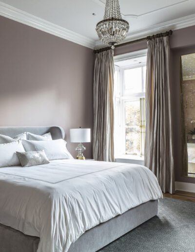 A bedroom with grey walls and a bed.