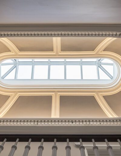 An ornate ceiling in a building with a staircase.