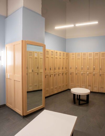 A locker room with wooden lockers and a mirror.