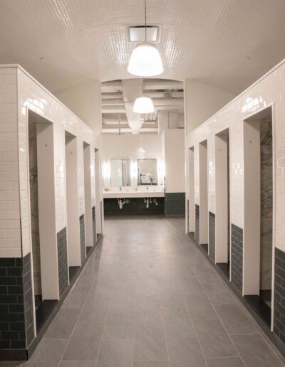 A long hallway with tiled walls and stalls.