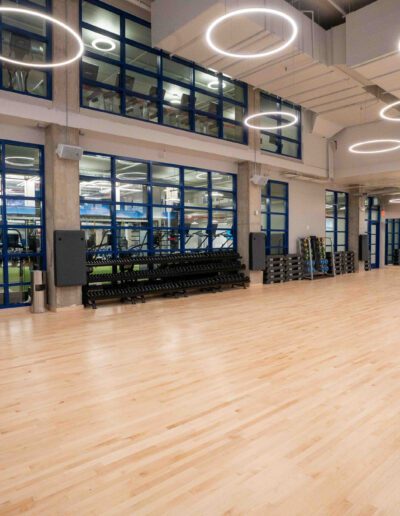 A gym with wooden floors and large windows.