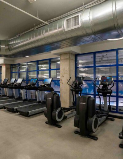 A gym with tread machines and large windows.