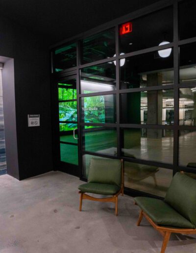 A hallway with a green chair in front of a glass door.