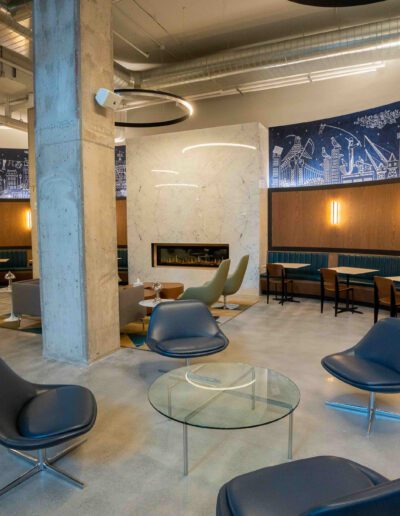 The lobby of a modern office building is decorated with blue chairs and a fireplace.