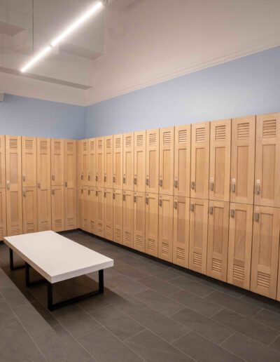 A locker room with wooden lockers and a bench.