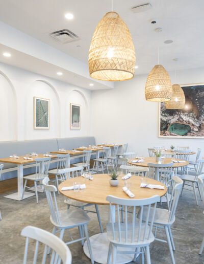 An empty restaurant with white tables and chairs.